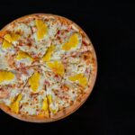 Pizzeria rodzinna od 1998: recenzja klasyków i tego, co się zmieniło Pizza hawajska z serem i ananasem na ciemnym tle